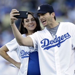Ahston Kutcher macht ein Selfie von sich und Mila Kunis in Baseball-Outfits der Dodgers.