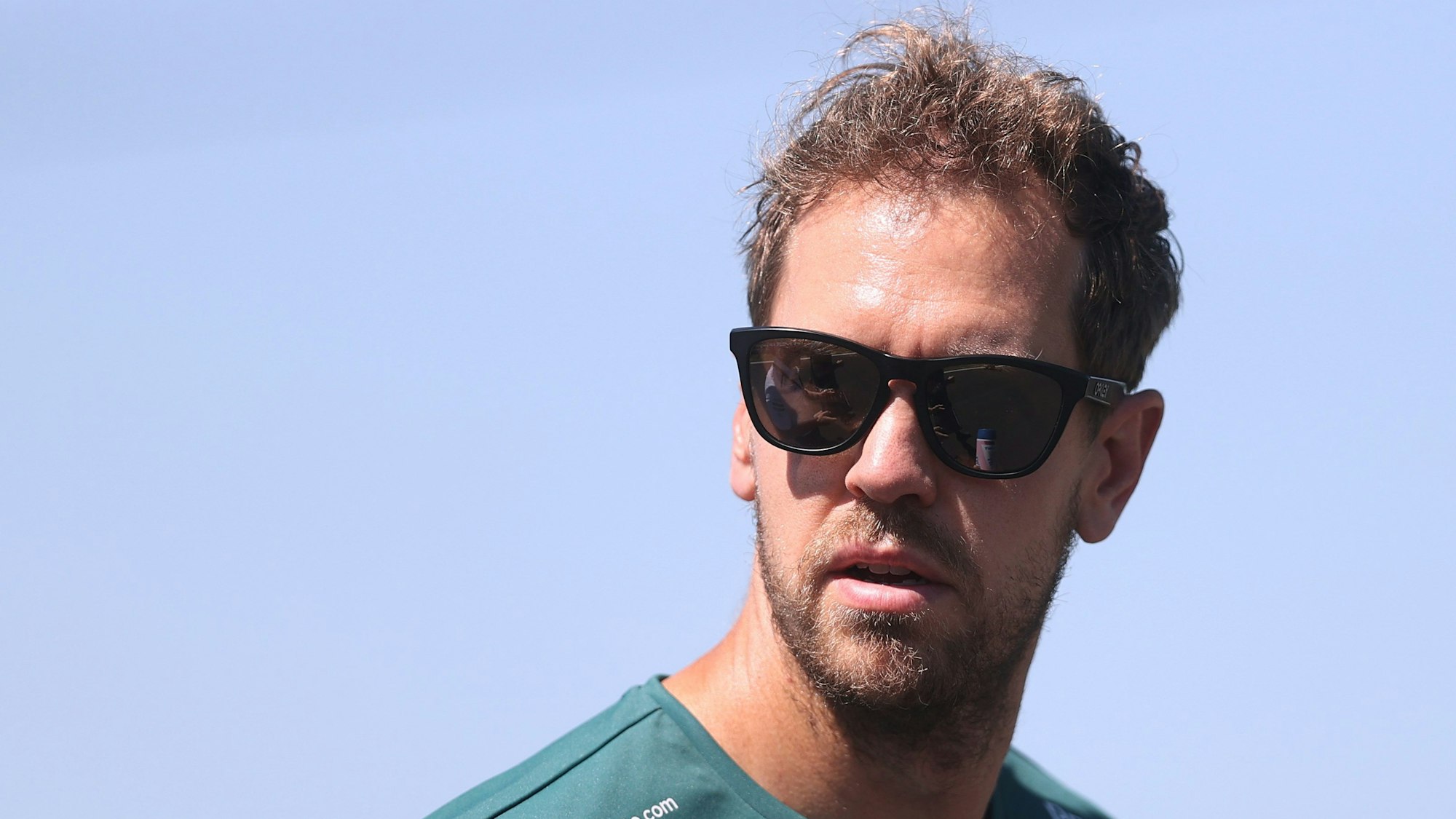 Sebastian Vettel guckt mit Sonnenbrille in die Kamera.