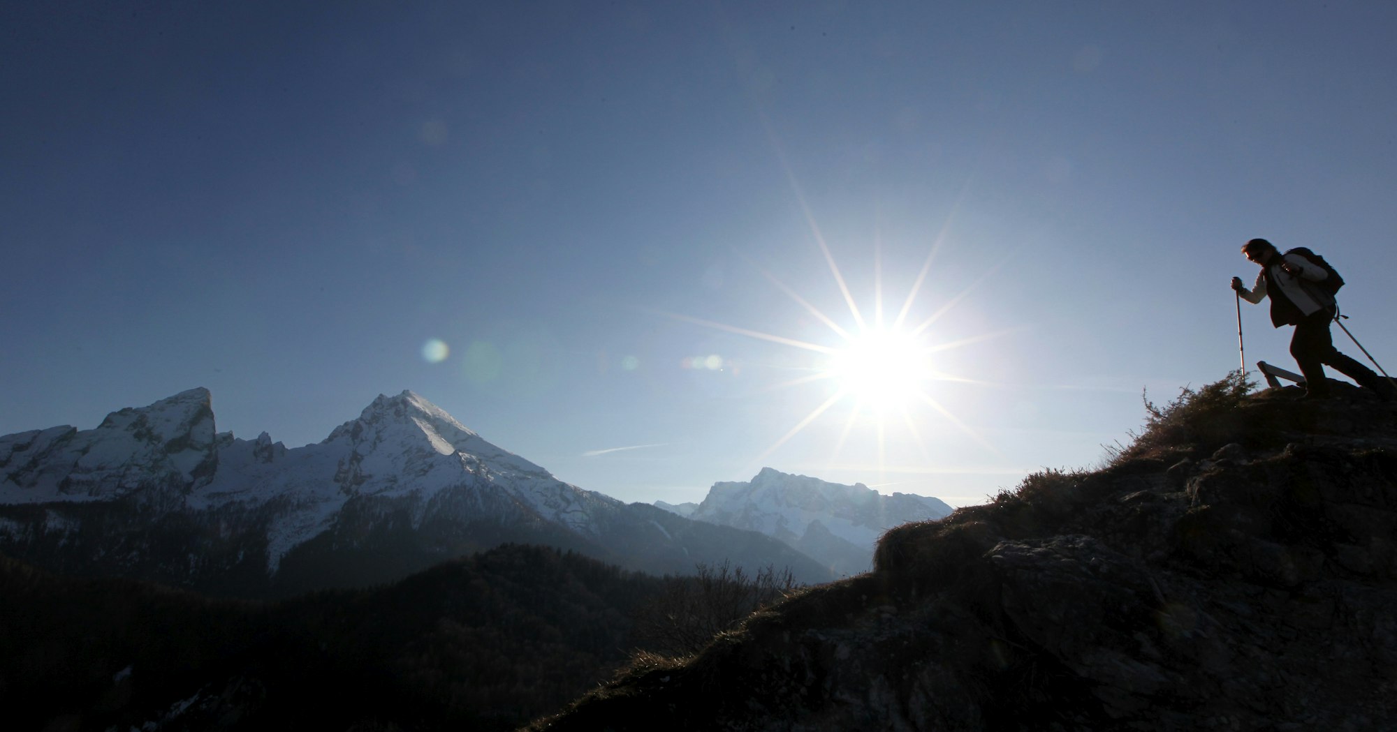 Eine Bergwanderin geht im April 2010 vor der Kulisse des Watzmanns durch die Bergwelt des Berchtesgadener Landes.