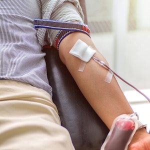 Ein Blutspender hat eine Kanüle im Arm, über die Blut entnommen wird (Symbolfoto).