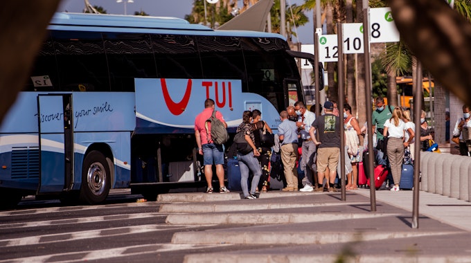 Touristen mit Mundschutz holen ihr Gepäck aus einem Bus auf den Kanarischen Inseln.