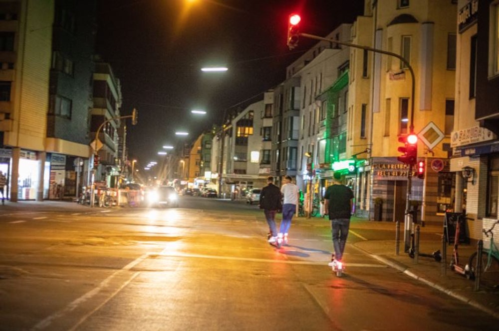 Männer fahren nachts mit E-Scootern über die Berrenrather Straße.