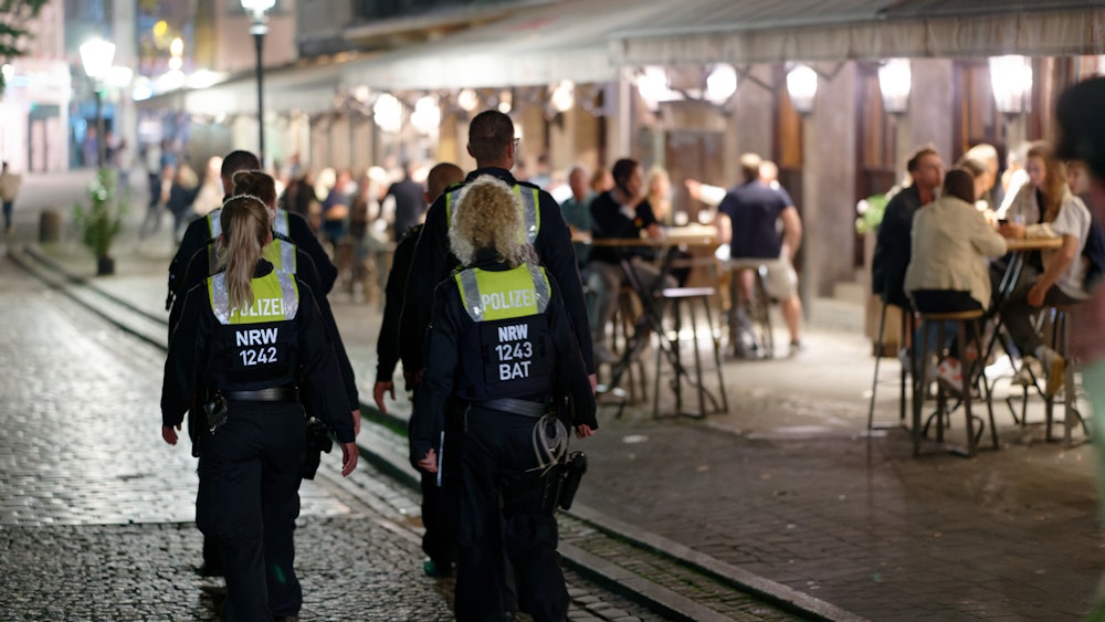 Polizisten und Polizistinnen im Dienst patrouillieren nach Mitternacht in der Düsseldorfer Altstadt zwischen Feiernden.