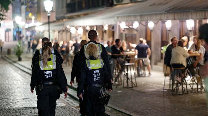 Polizisten und Polizistinnen im Dienst patrouillieren nach Mitternacht in der Düsseldorfer Altstadt zwischen Feiernden.