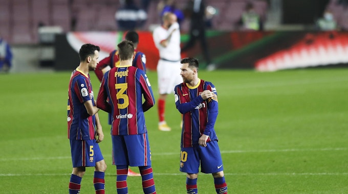 Sergio Busquets und Gerard Pique reden bei einem Spiel des FC Barcelona mit Lionel Messi.