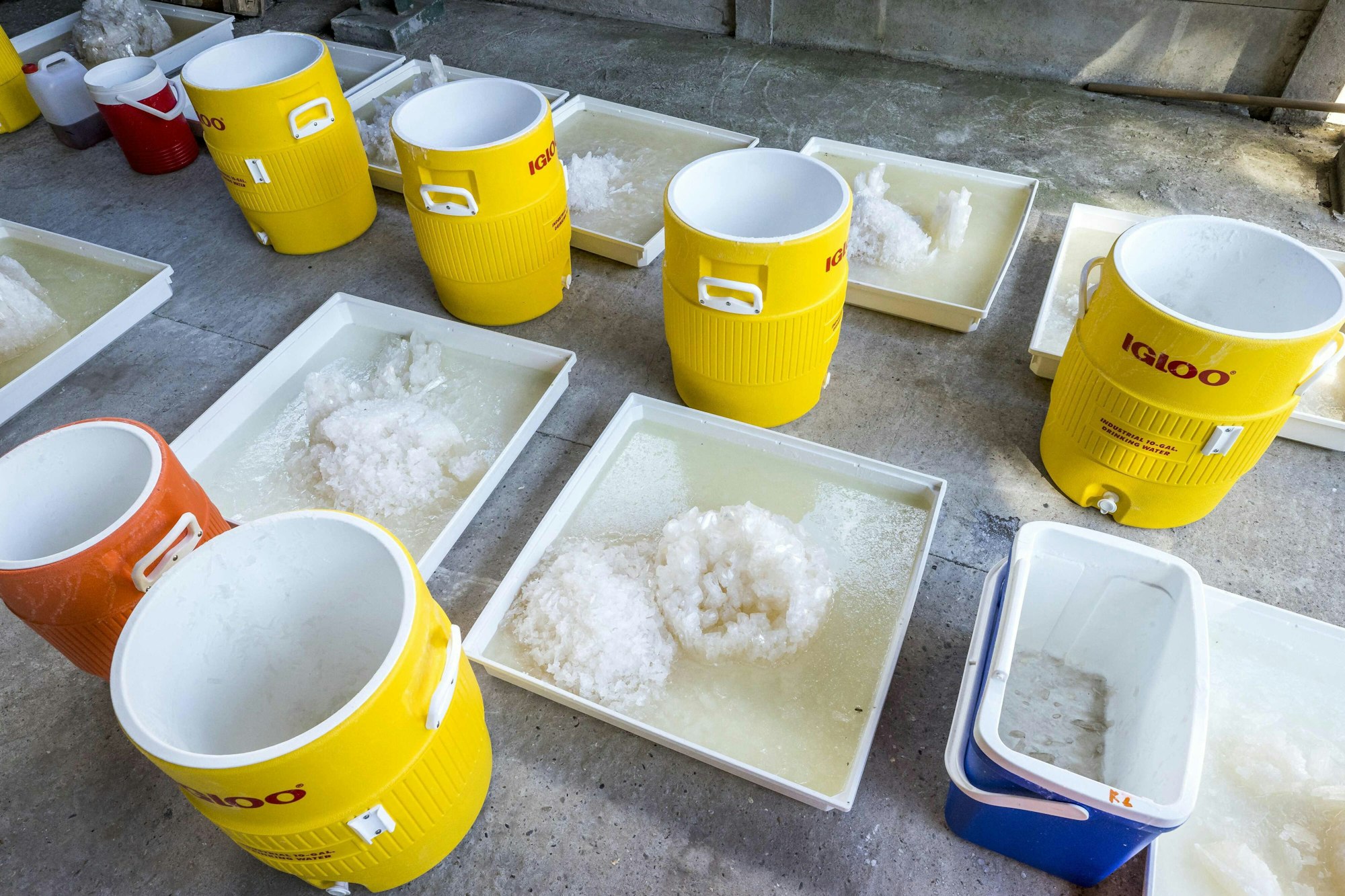 In einem Drogenlabor stehen gelbe Fässer, daneben quadratische Becken mit Kristallen von Methamphetamin.