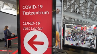 Zahlreiche Reisende stehen am Morgen an den Schaltern in einer der Abfertigungshallen des Frankfurter Flughafens (u.r.) während es links zum Covid-19-Testzentrum geht.