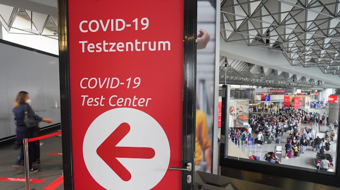 Zahlreiche Reisende stehen am Morgen an den Schaltern in einer der Abfertigungshallen des Frankfurter Flughafens (u.r.) während es links zum Covid-19-Testzentrum geht.