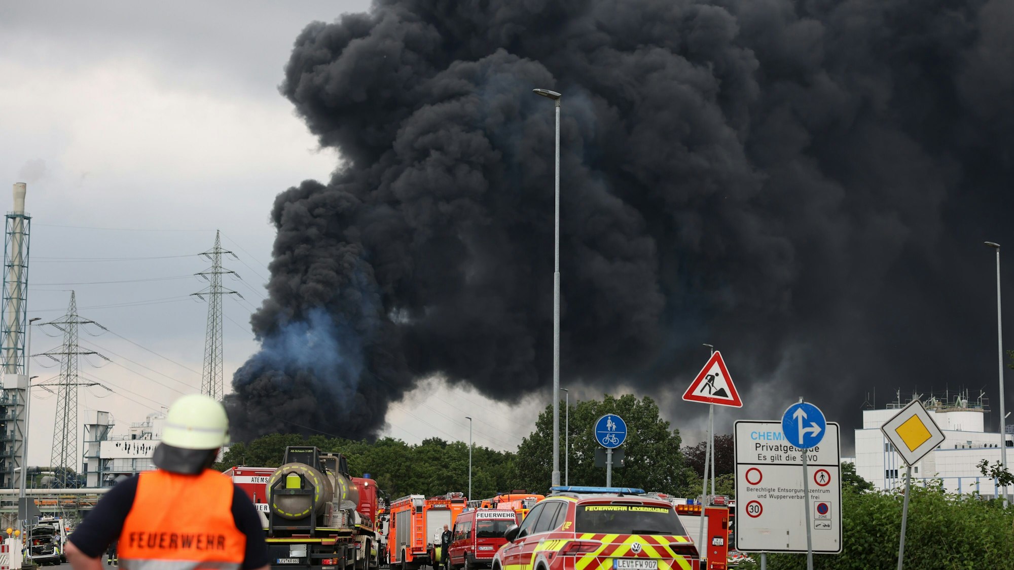 Einsatzfahrzeuge der Feuerwehr stehen am 27. Juli unweit einer Zufahrt zum Chempark über dem eine dunkle Rauchwolke aufsteigt. Die Explosion löste einen Brand aus.