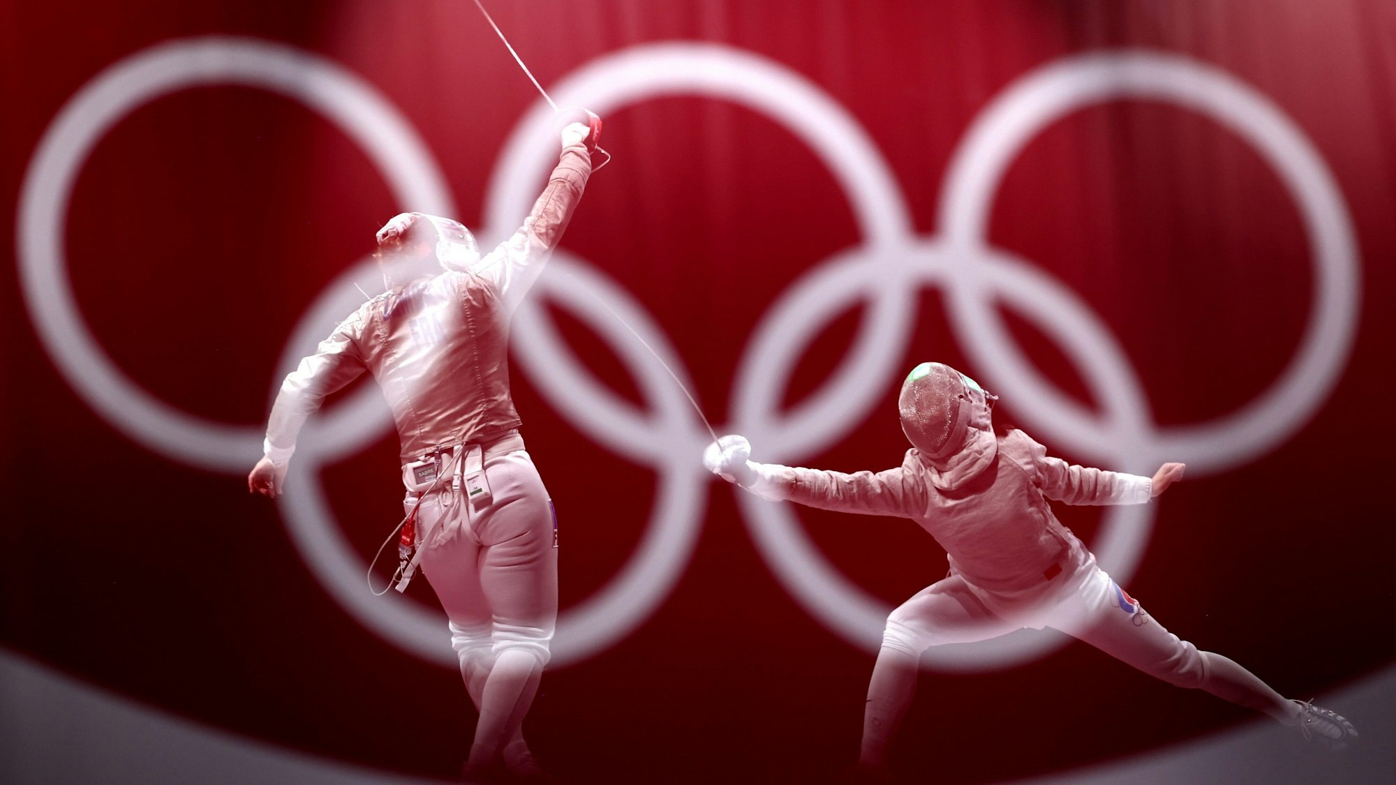 Zwei Fechterinnen duellieren sich, im Vordergrund prangen die Olympischen Ringe.
