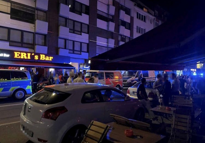 Polizeiautos und ein Rettungswagen stehen nachts auf der Zülpicher Straße.