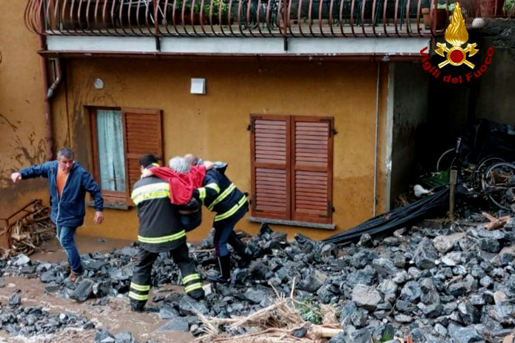 Einsatzkräfte der Feuerwehr retten eine ältere Frau aus ihrem Haus in Laglio am Comer See.