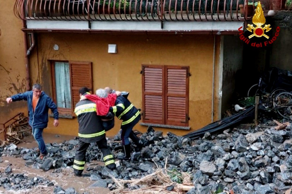 Einsatzkräfte der Feuerwehr retten eine ältere Frau aus ihrem Haus in Laglio am Comer See.