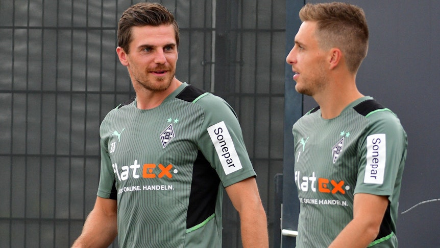Gladbachs Nationalspieler Jonas Hofmann (links) betritt gemeinsam mit Team-Kollege Patrick Herrmann (rechts) am 27. Juli 2021 das Trainingsgelände im Borussia-Park. Die beiden unterhalten sich dabei, Hofmann schaut zu Herrmann rüber.