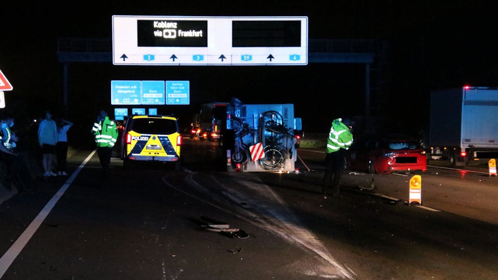 Einsatzkräfte sowie ein Polizeifahrzeug stehen nachts auf der Autobahn.