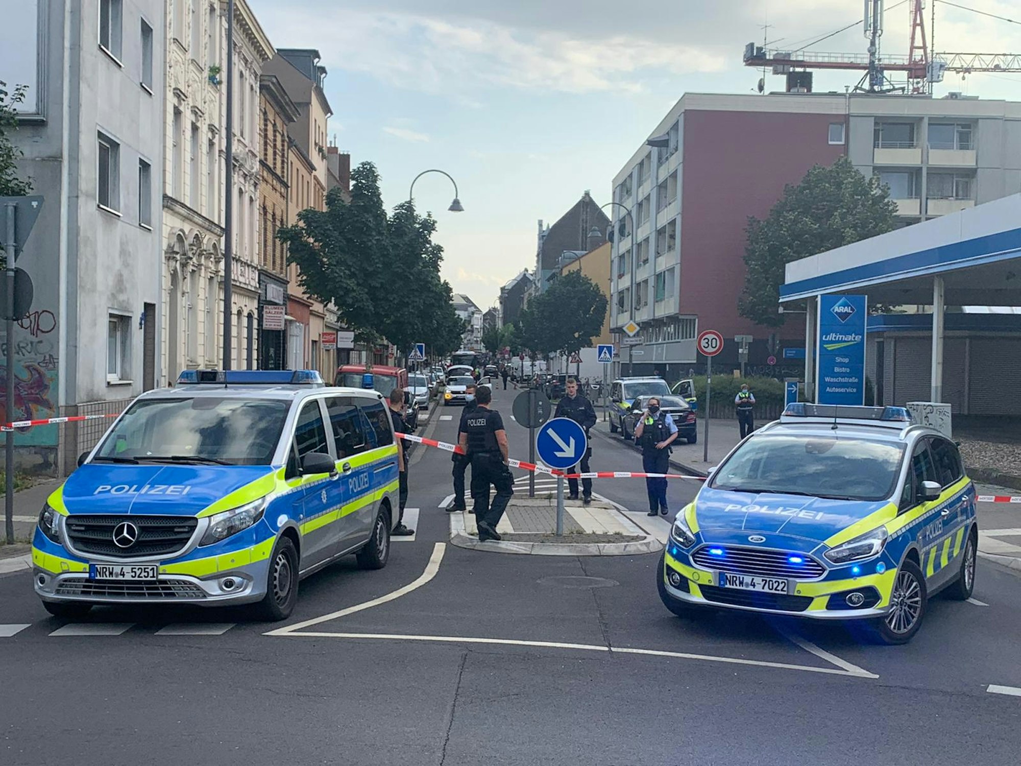 02.08.2021, Köln: Ein Auto steht hinter einer Polizeiabsperrung auf der Berliner Straße. Ersten Informationen zufolge soll sich in dem Fahrzeug eine Handgranate befinden.