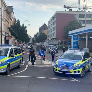 02.08.2021, Köln: Ein Auto steht hinter einer Polizeiabsperrung auf der Berliner Straße. Ersten Informationen zufolge soll sich in dem Fahrzeug eine Handgranate befinden.