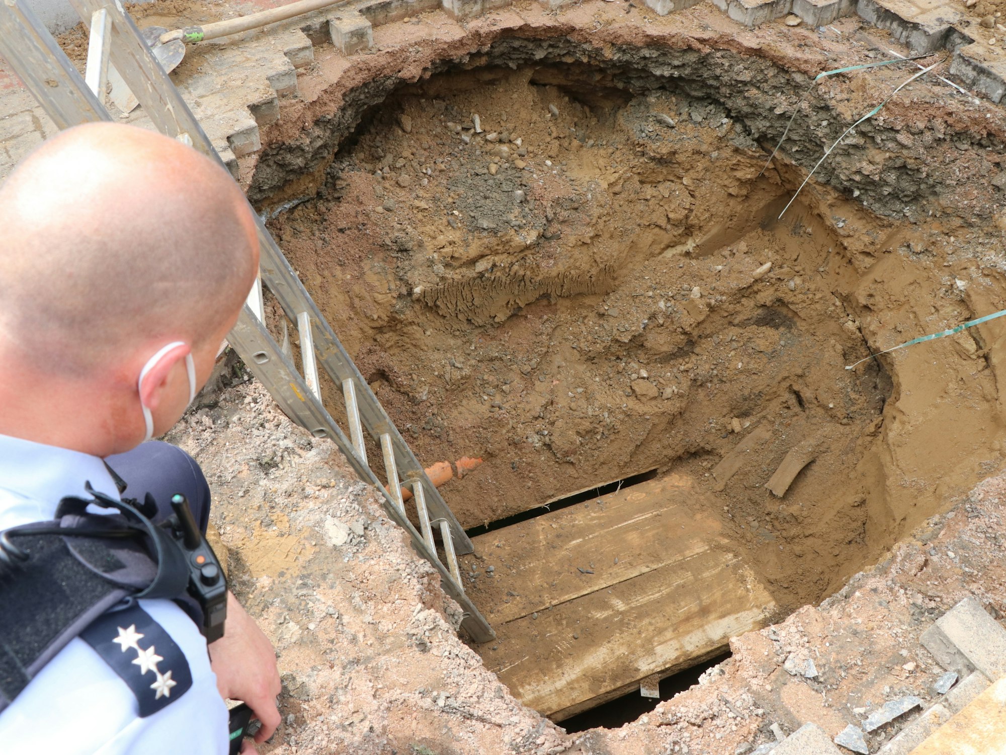 Ein Polizist schaut auf das Loch eines Tunnels, den Unbekannte zur Volksbank gegraben haben.