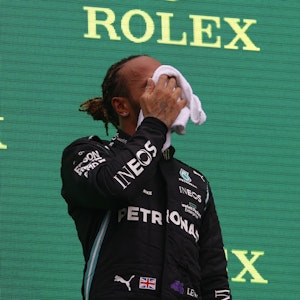 Formel 1: Lewis Hamilton wischt sich das Gesicht trocken auf dem Podium.