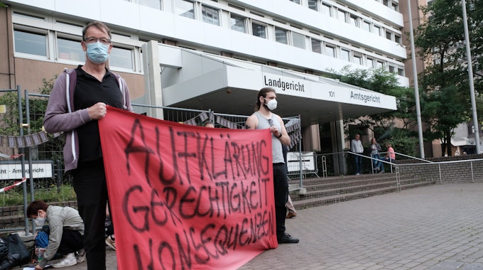 Demonstranten halten ein Plakat vor dem Kölner Landgericht hoch.