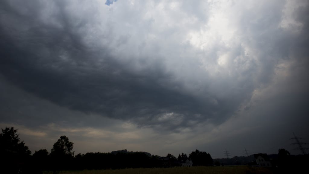 Dunkle Gewitterwolken ziehen über ein Feld in Hattingen (Nordrhein-Westfalen).
