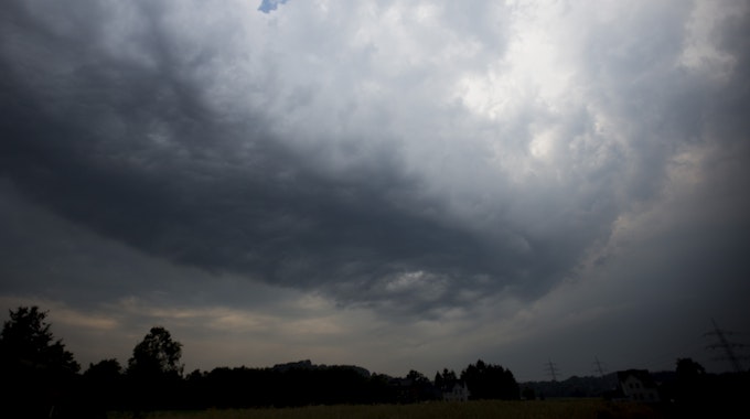 Dunkle Gewitterwolken ziehen über ein Feld in Hattingen (Nordrhein-Westfalen).