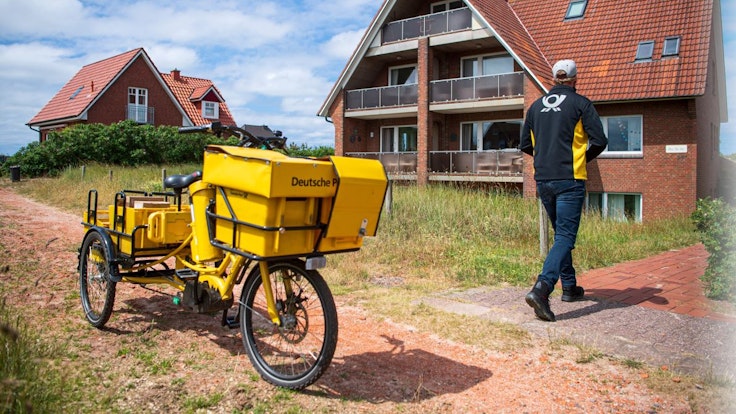 Ein Postbote bringt Post zu einem Haus auf Baltrum.