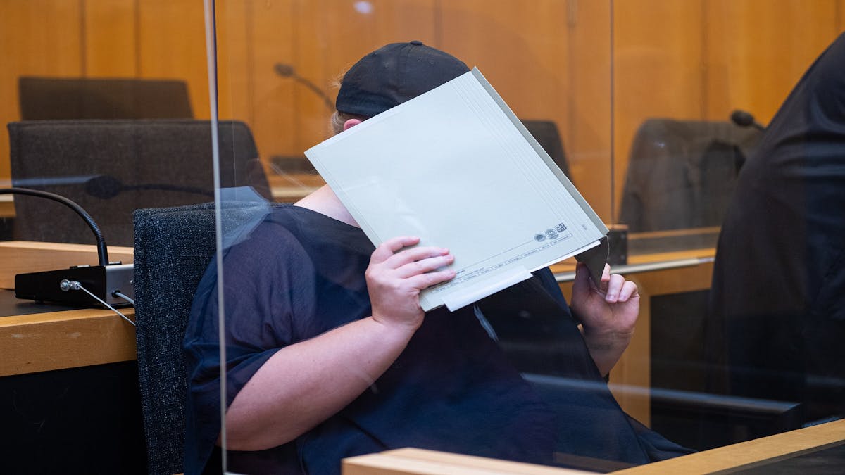 Zu Beginn des Prozesses im Missbrauchskomplex Münster sitzt die Mutter eines Opfers im Landgericht Münster und verdeckt ihr Gesicht mit einer Mappe.&nbsp;