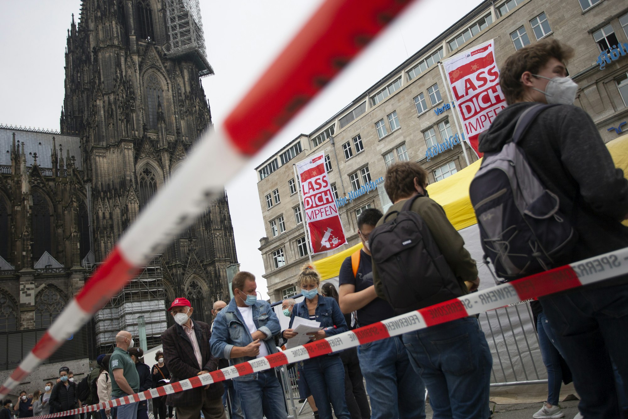 Menschen stehen Schlange bei einer Corona-Impfaktion der Stadt Köln vor dem Hauptbahnhof und Kölner Dom.