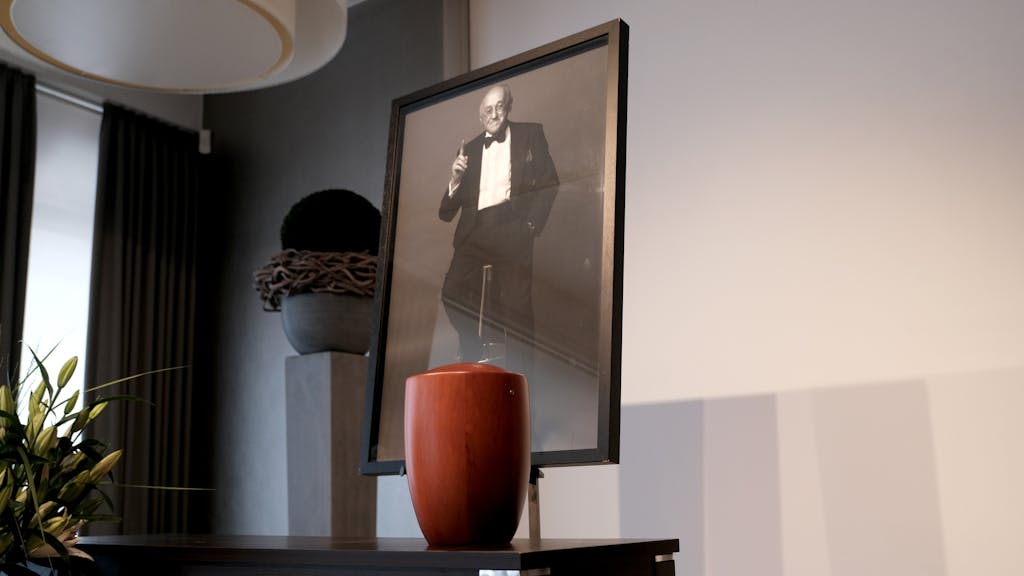Die Urne von Alfred Biolek, dahinter ein Foto von ihm, steht in einem Raum.