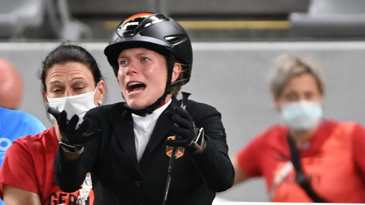 Annika Schleu hebt beim Springreit-Wettbewerb des Olympischen Fünfkampfes in Tokio klagend die Arme.