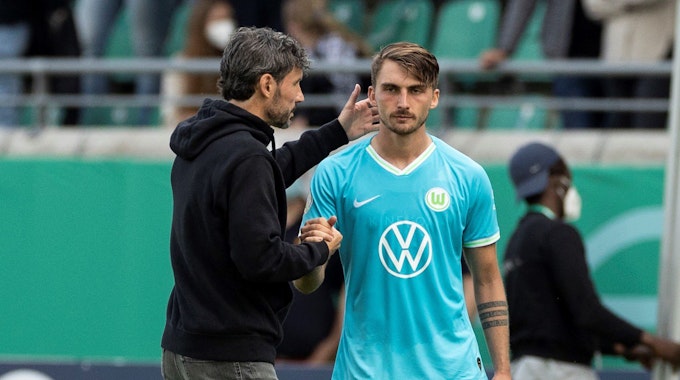 Wolfsburgs Trainer Mark van Bommel (l) steht vor der Einwechslung mit Maximilian Philipp zusammen.