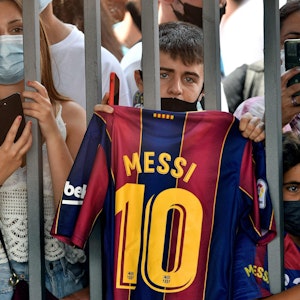 Ein Fan hält ein Barca-Trikot von Lionel Messi in die Luft