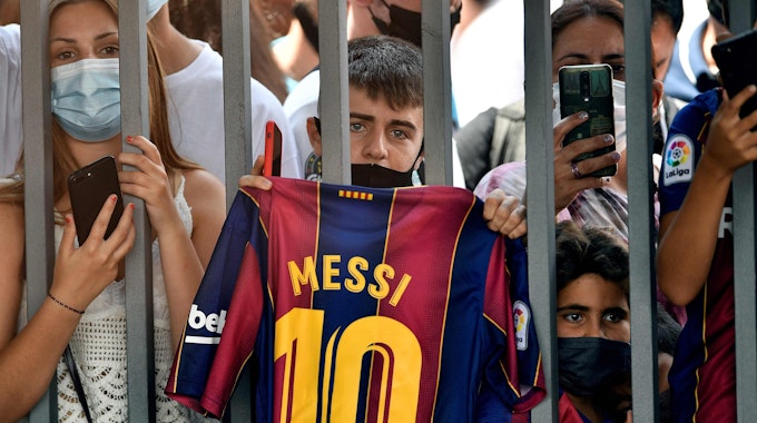 Ein Fan hält ein Barca-Trikot von Lionel Messi in die Luft