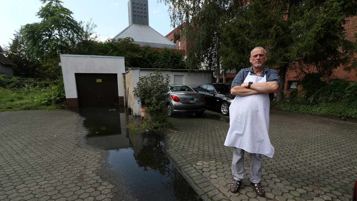 Konditormeister Udo Robl steht neben einer Pfütze und in seinem Geschäft Feine Torte in Niehl. 