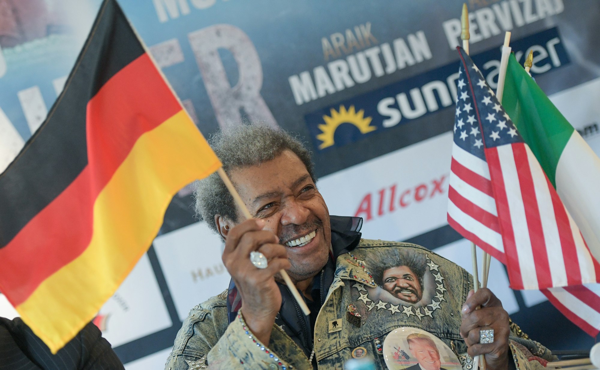 Don King, US-Boxpromoter, schwenkt während der Pressekonferenz eine deutsche Flagge, während er weitere Fähnchen in der Hand hält.