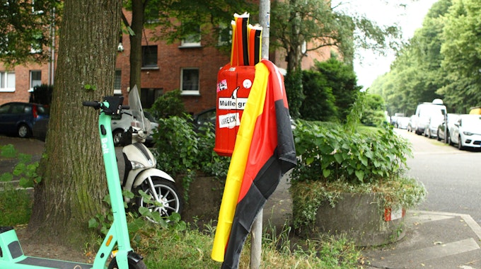 Plastik-Klatschstangen in den Farben von Deutschland sowie eine Deutschland-Fahne in einem Mülleimer.