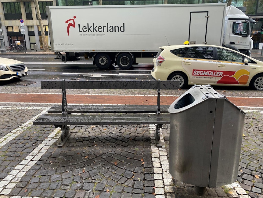 Eine Bank neben einem Mülleimer auf dem Hohenzollernring in Köln.