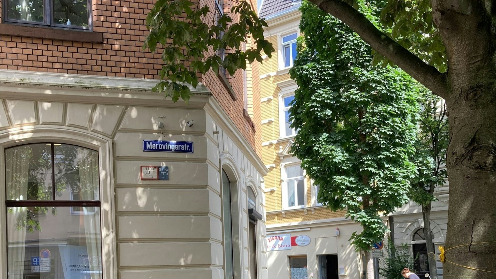In der Merowingerstraße gibt es ein Schild mit anderer Schreibweise, hier heißt es Merovingerstraße. Bei den blauen Straßennamensschildern handelt es sich um eine historische Beschilderung.