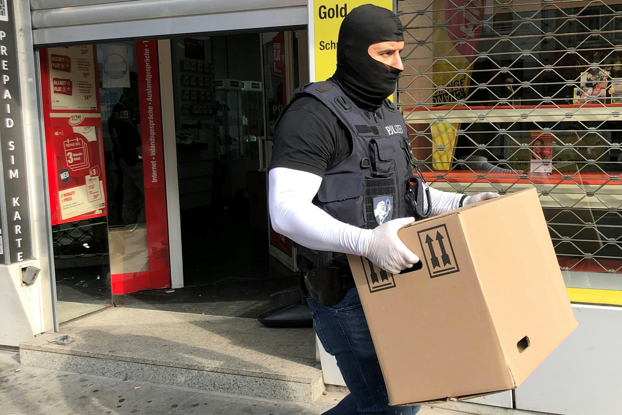 Ein Polizist trägt mögliche Beweismittel aus einem Laden in der Düsseldorfer Innenstadt.