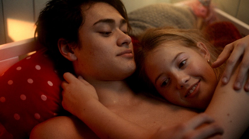 Ein Junge und ein Mädchen liegen mit nackten Oberkörpern im Bett und kuscheln.