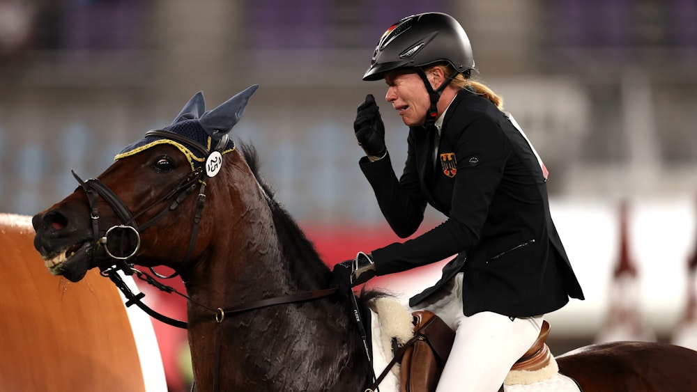 Annika Schleu sitzt bei Olympia weinend auf ihrem Pferd „Saint Boy“.