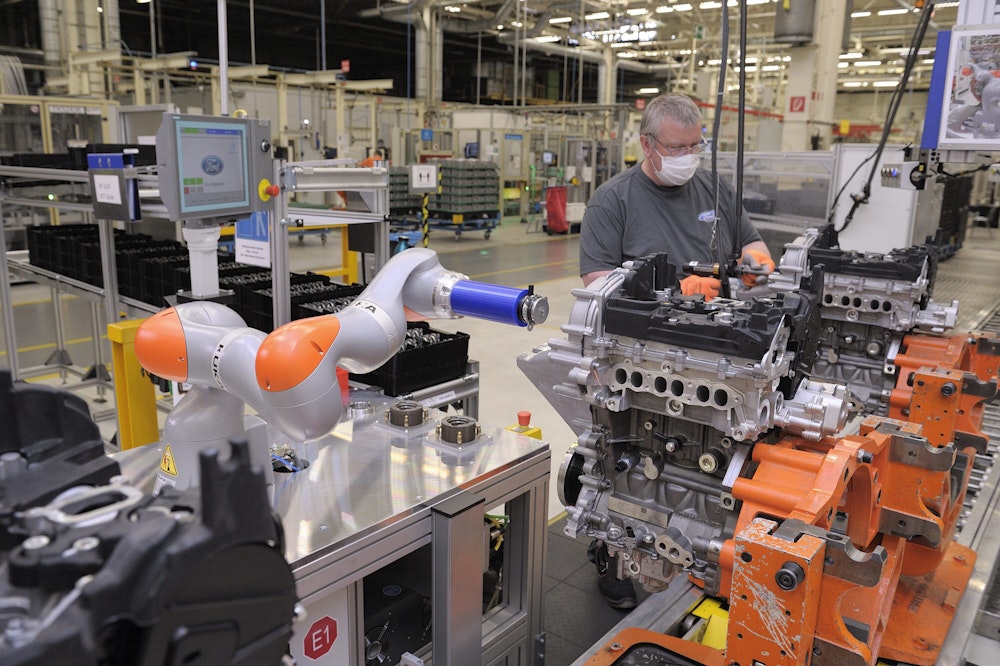 Ein Roboter arbeitet bei Ford mit einem Mitarbeiter zusammen an einem Motorblock.