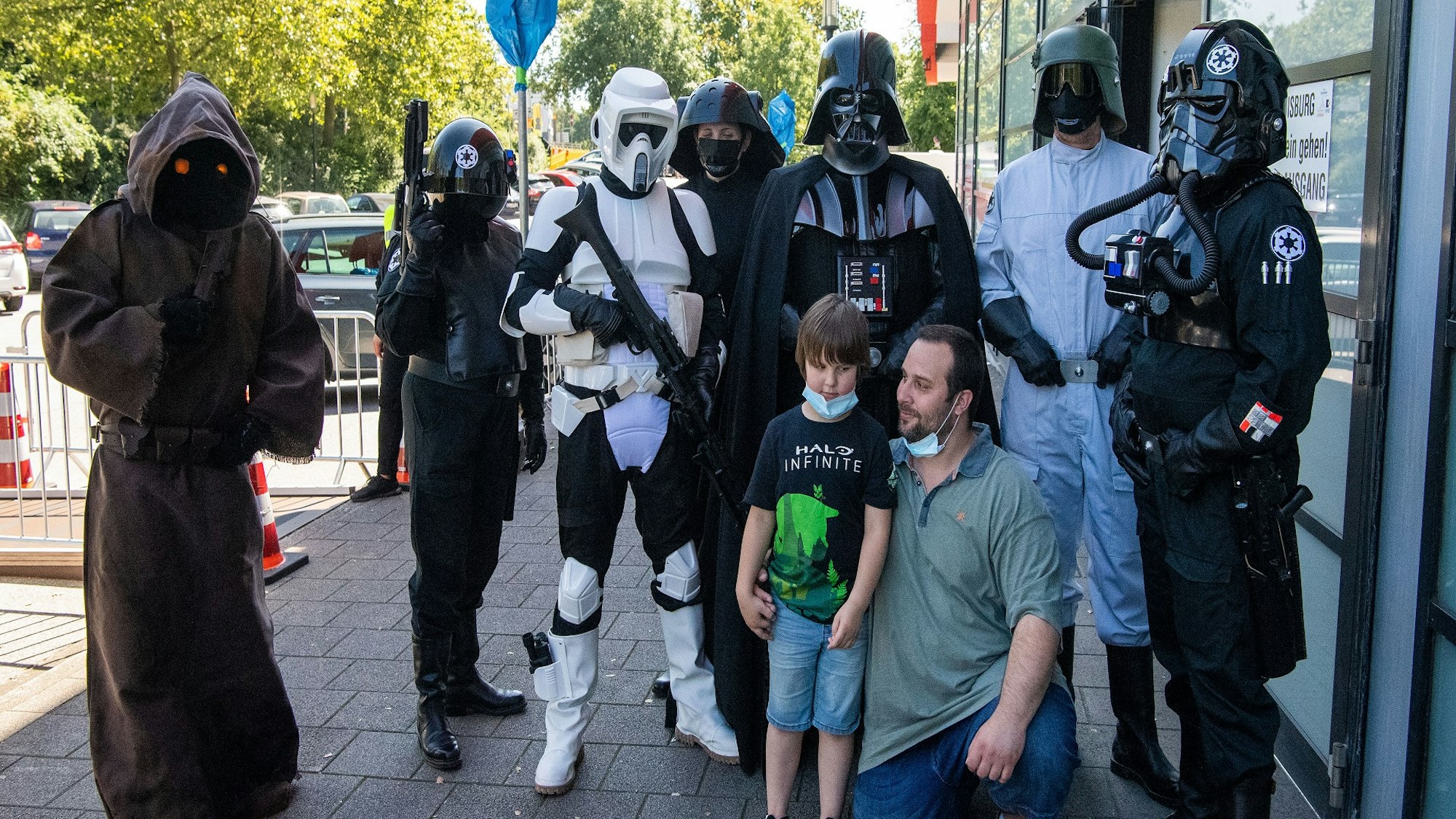 Philipp Oszcera und sein Sohn Luke lassen sich von seiner Frau Nadine mit Darstellern in Kostümen aus der Filmreihe Star Wars vor dem Duisburger Impf-Zentrum fotografieren.