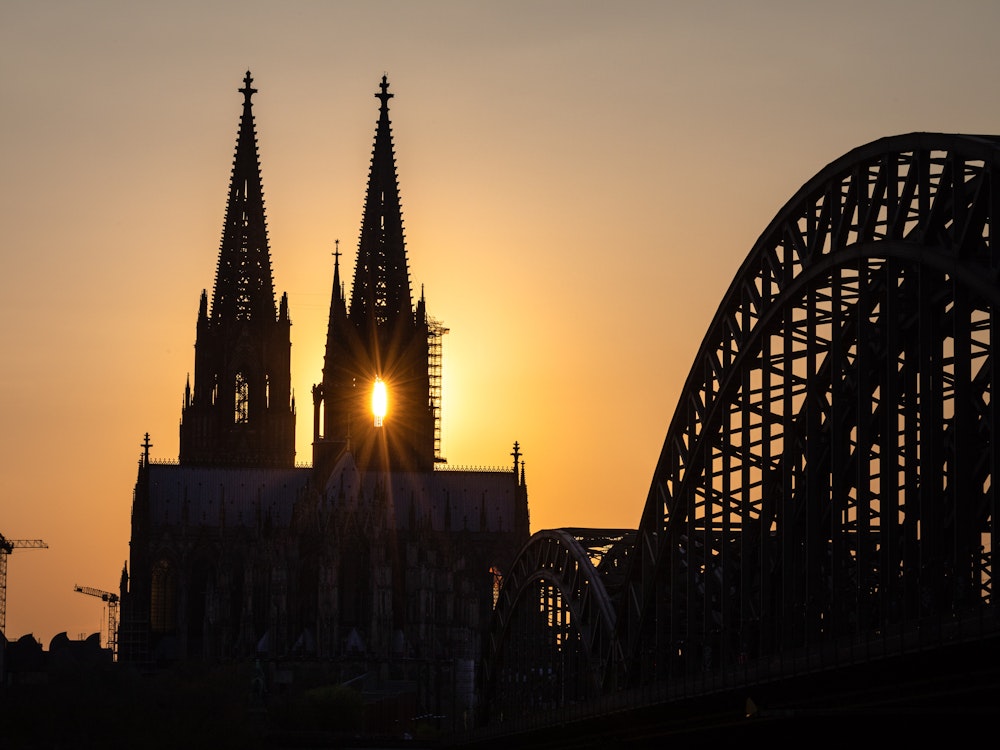 Die Sonne geht hinter dem Kölner Dom unter.