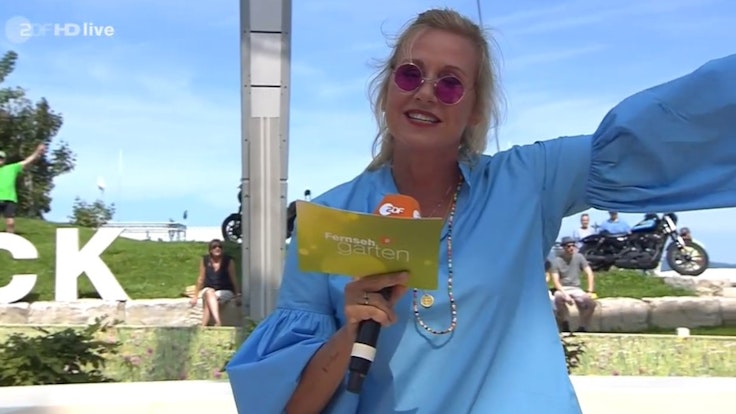 Andrea Kiewel moderiert in einem "Festivaloutfit" mit John Lennon-Brille den ZDF-Fernsehgarten am 15. August