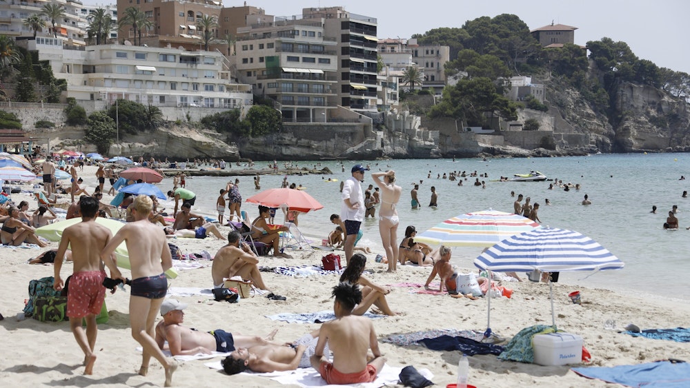 Einheimische und Touristen kühlen sich im Meer am Strand Cala Major in Palma de Mallorca ab.