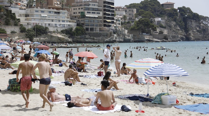 Einheimische und Touristen kühlen sich im Meer am Strand Cala Major in Palma de Mallorca ab.