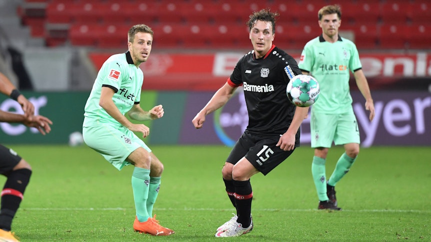 Gladbachs Patrick Herrmann ( und Leverkusens Julian Baumgartlinger am 08.November 2020 beim Bundesliga-Duell der beiden Klubs. Beide schauen dem Ball hinterher.