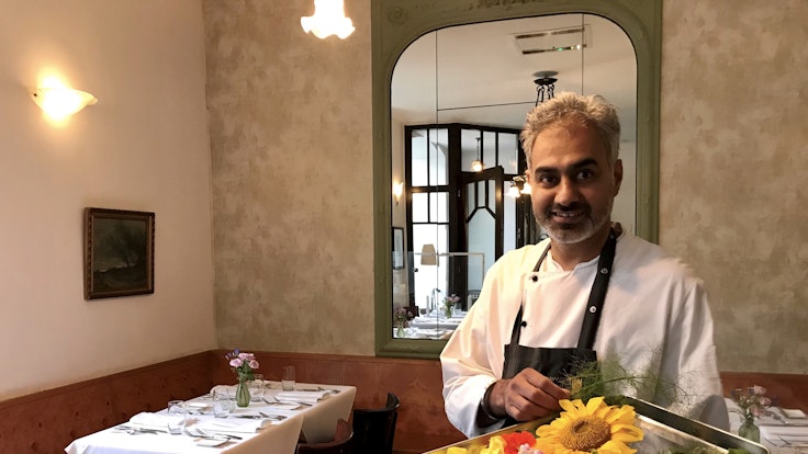 Jaspreet Dhaliwal-Wilmes steht mit einem Tablett Blüten in seinem Restaurant.